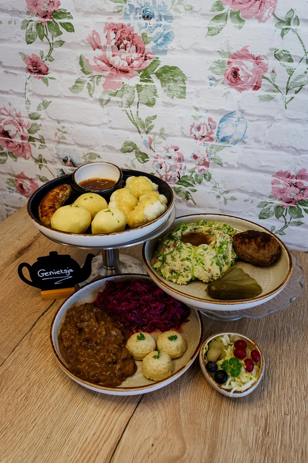 Een warme lunch op de tafel van het teehûs, met bloemetjesbehang op de achtergrond.